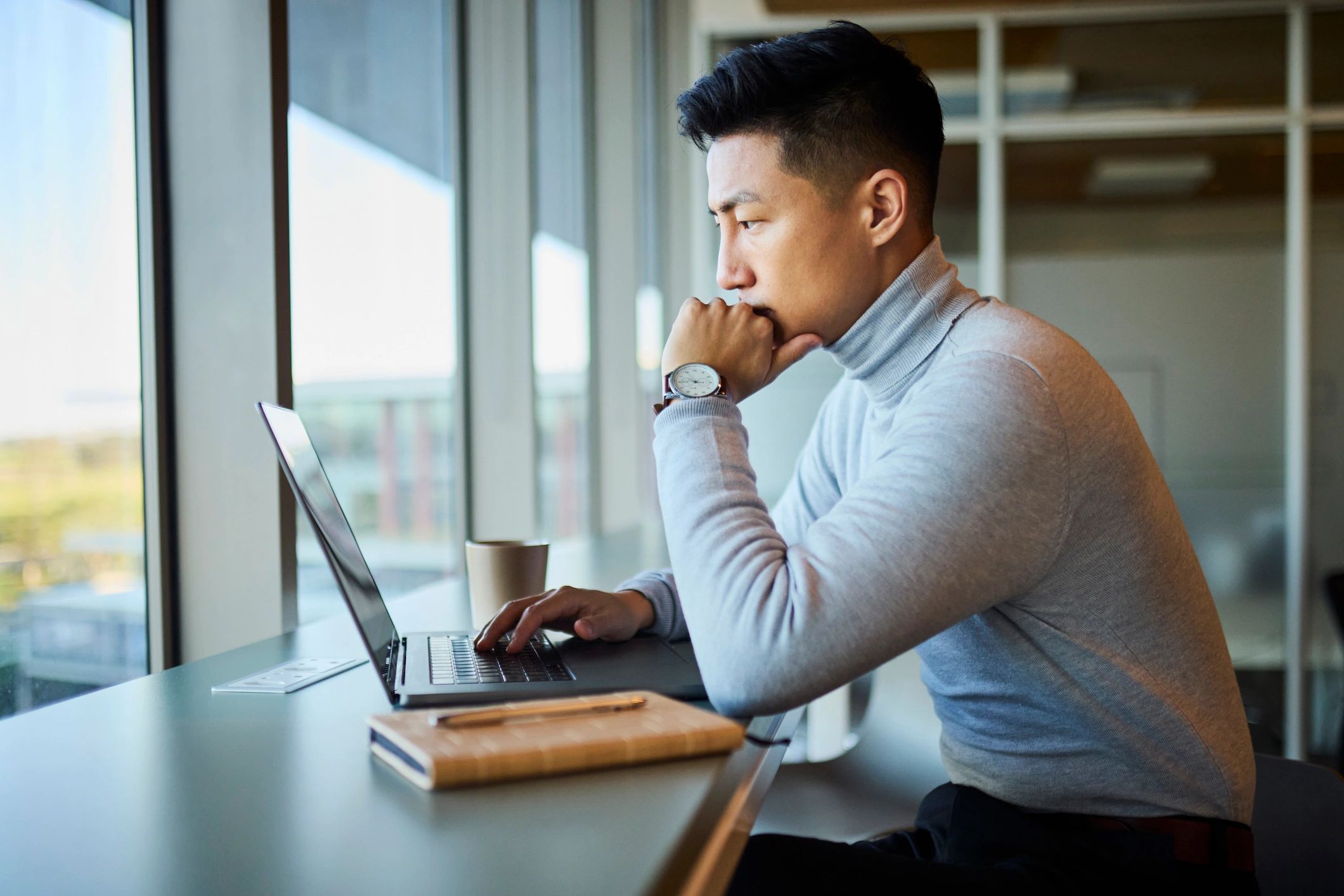 Analyst working on a laptop reviewing a dashboard in a modern office